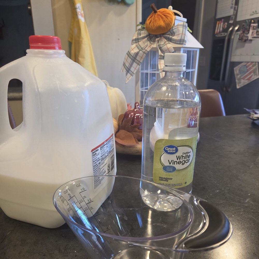 Milk, white vinegar, and a measuring cup on the counter